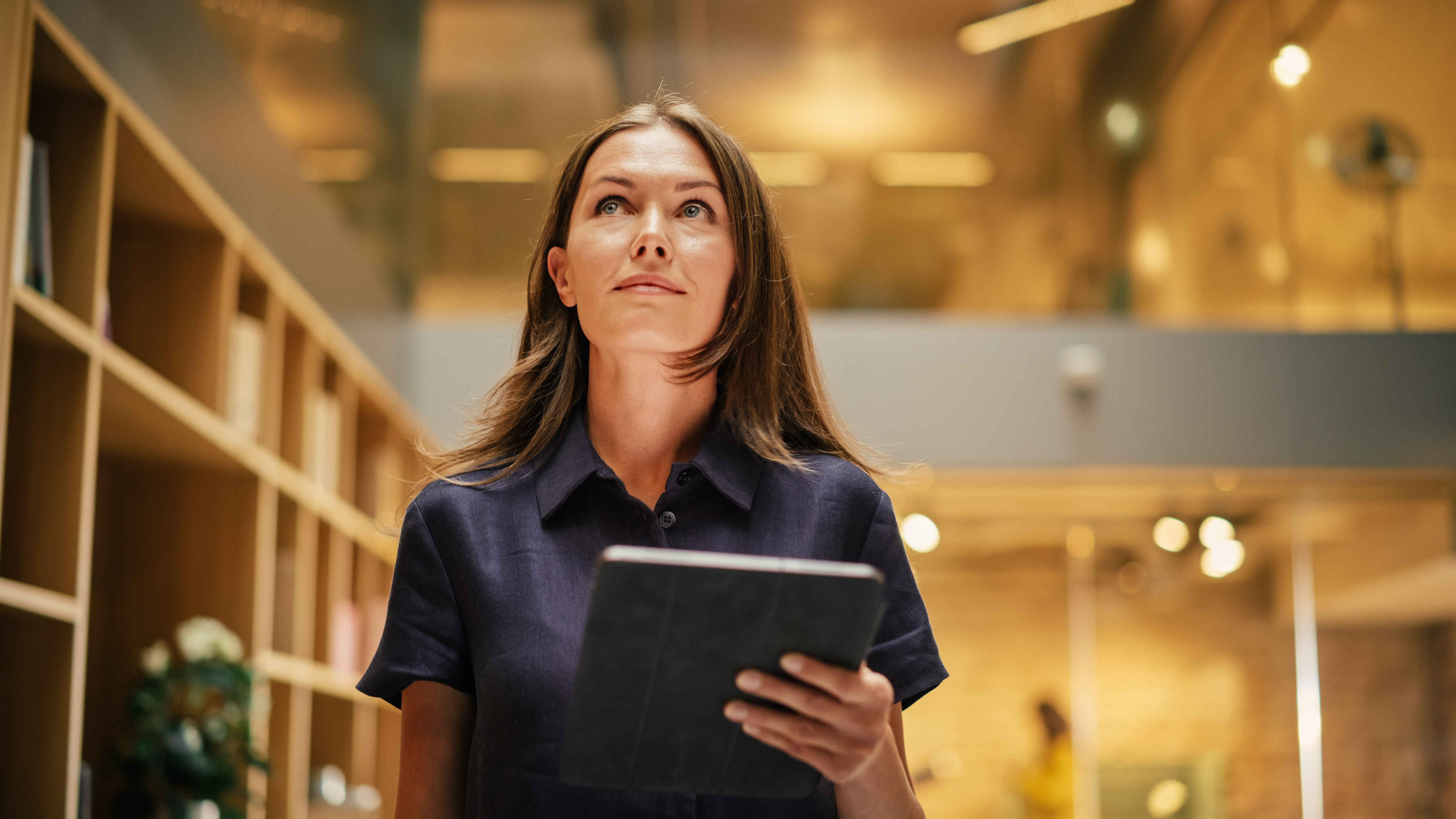 Eine Frau läuft mit einem Tablet in der Hand und schaut nach oben