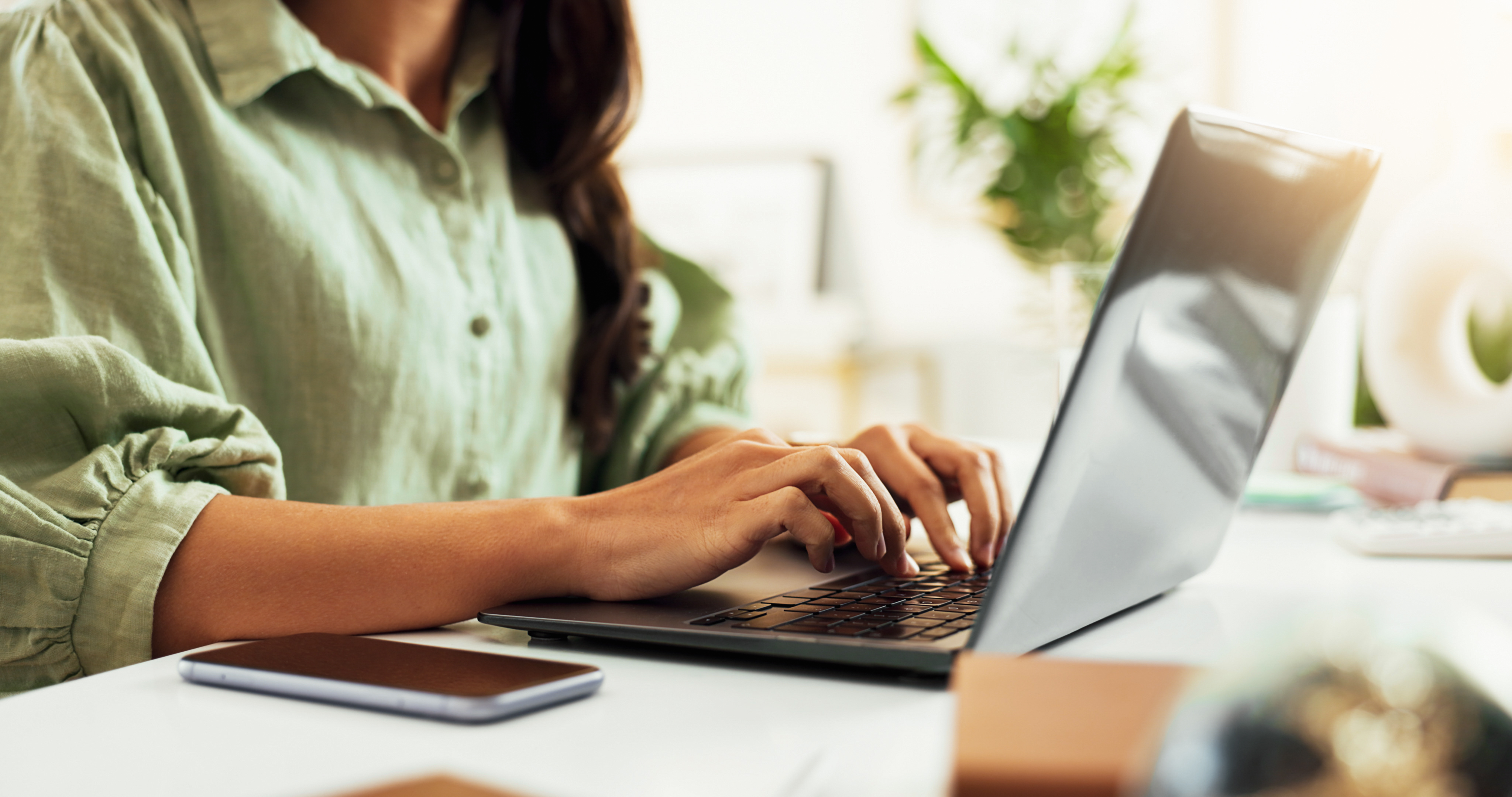 Großaufnahme von Frauenhänden die etwas auf einem Laptop tippen