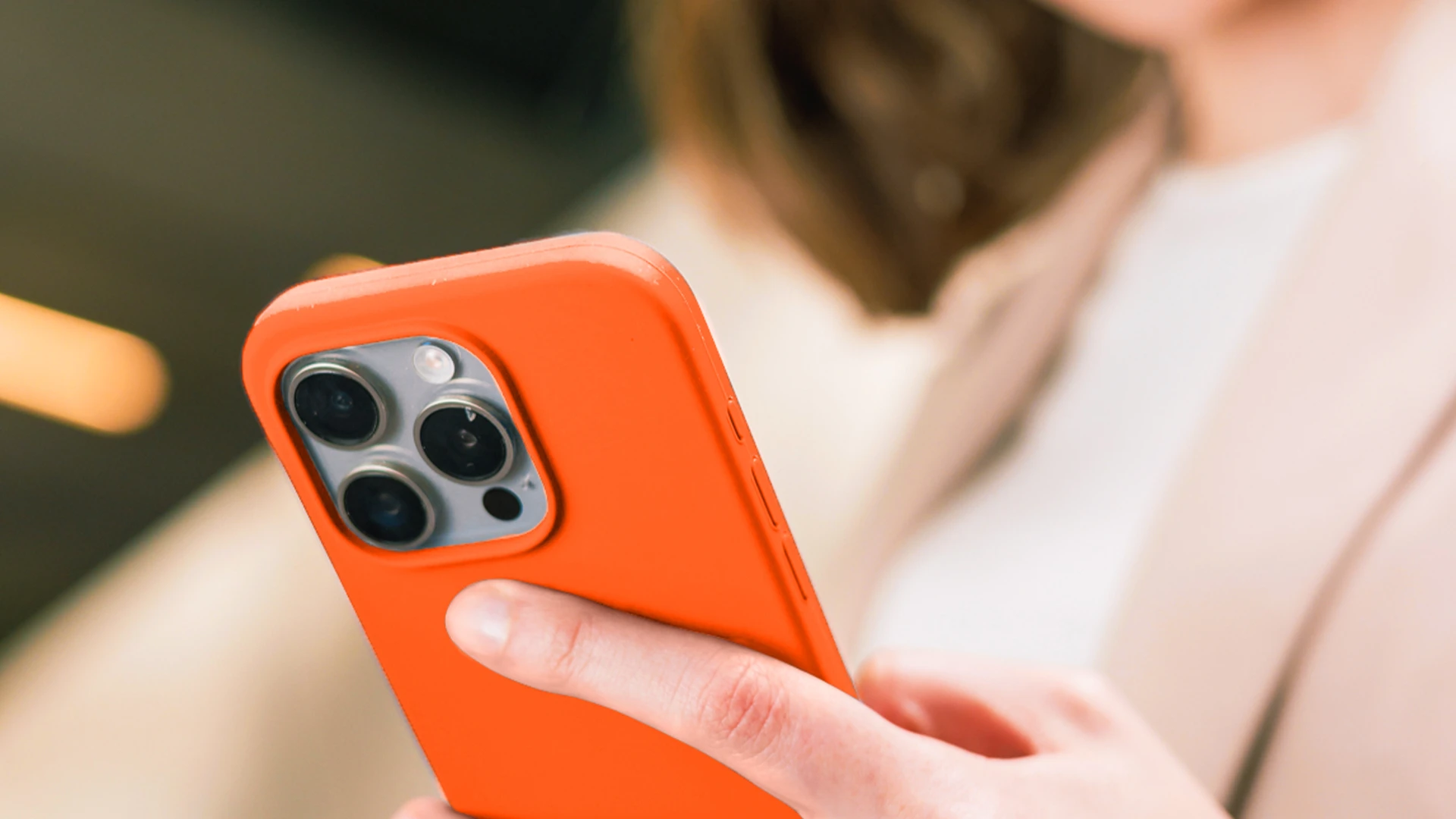 Frau, die ein oranges Smartphone in der Hand hält