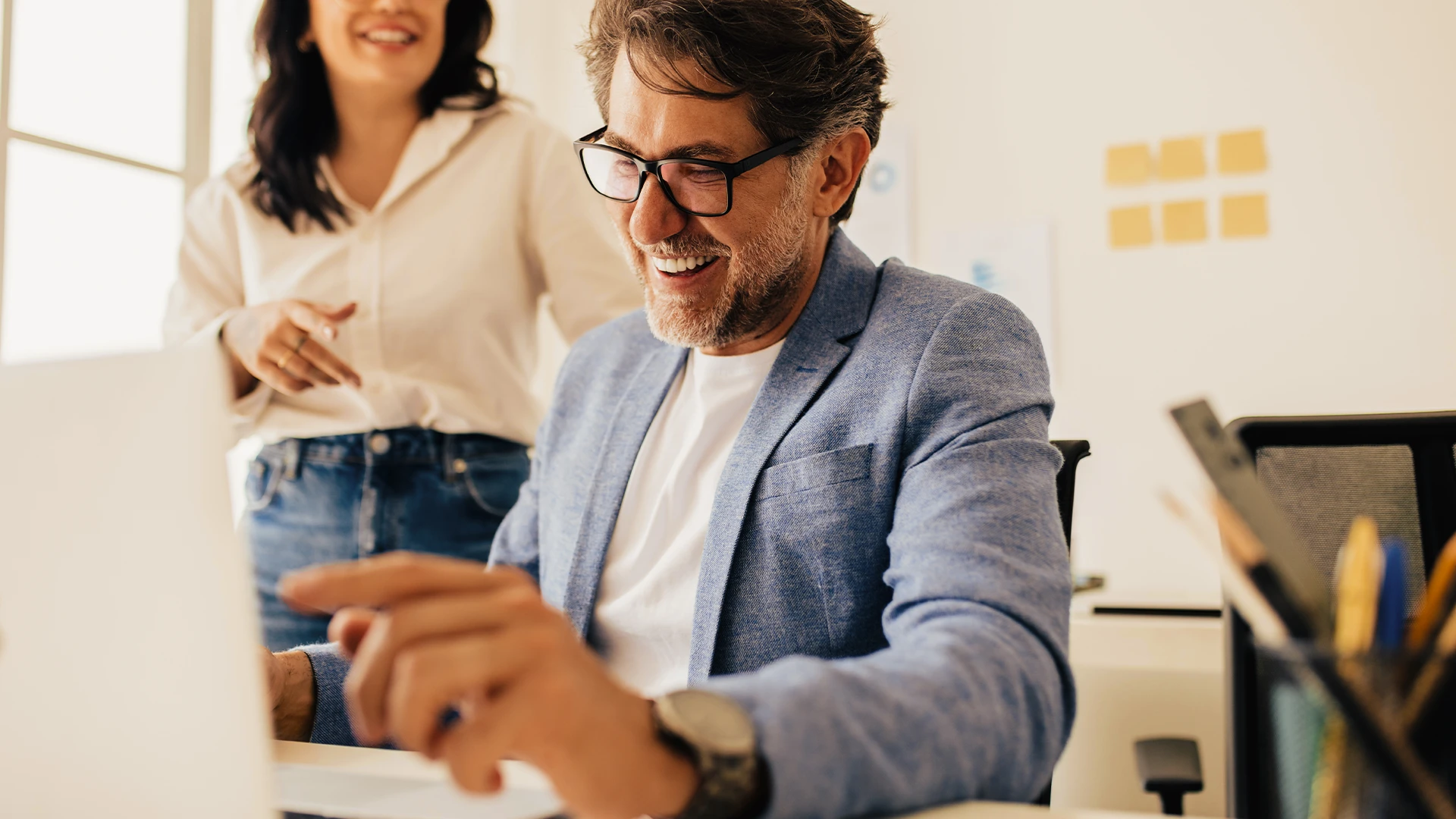 Mann, der lächelnd am Laptop im Büro sitzt