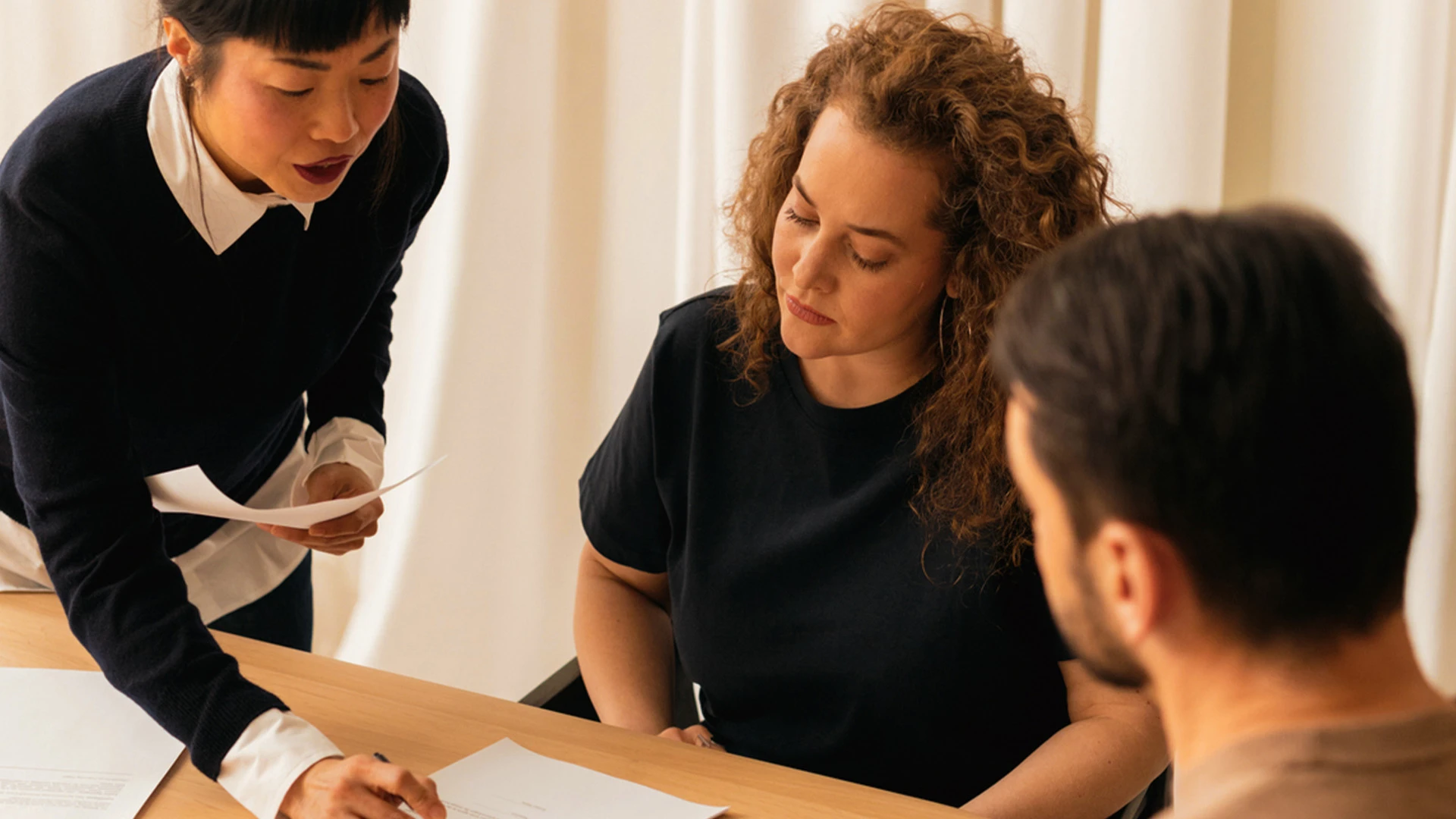Drei Personen in einer Situation in welcher ein Vertrag unterschrieben wird