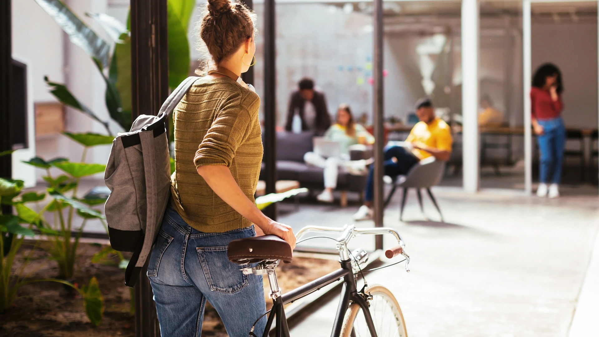 Rückansicht einer Frau die ihr Fahrrad in Richtung Office schiebt