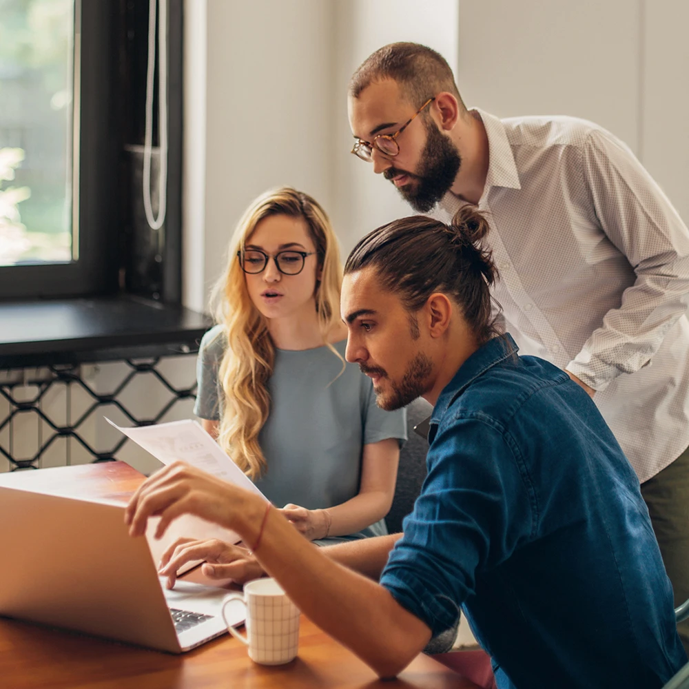 Gruppe junger Menschen, die gemeinsam auf einen Laptop Screen sehen