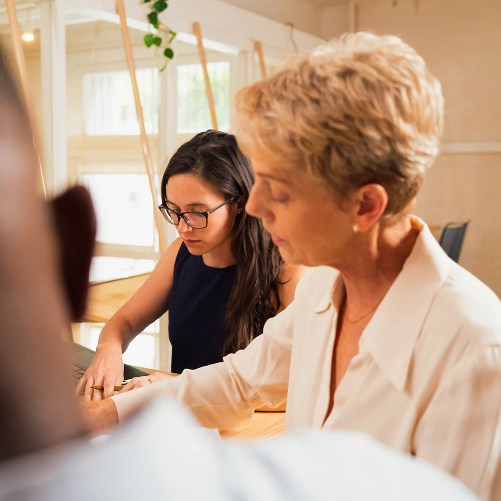Junge Frau in Arbeitssituation neben ihrer Mentorin