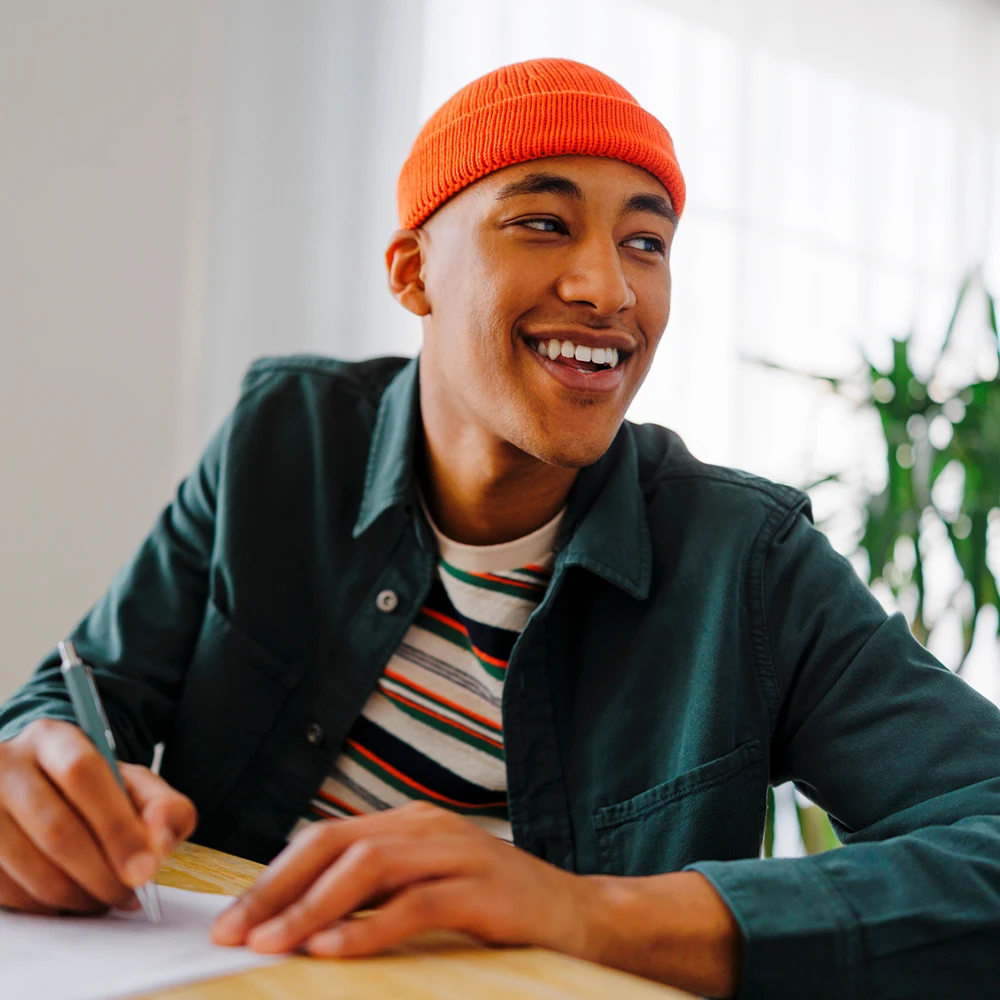 Junger, gut gelaunter Mann beim Verfassen eines Textes