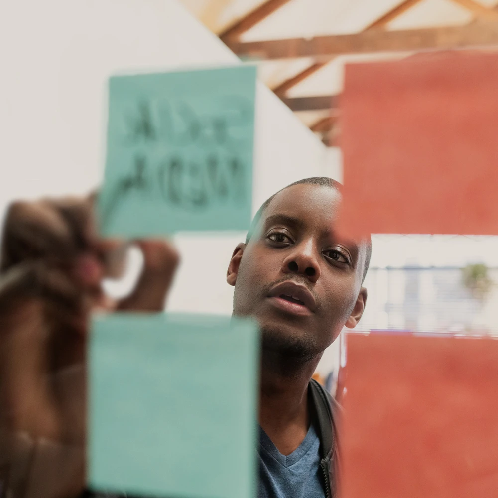 CloseUp einer Person, die mit PostIts arbeitet durch eine Glaswand fotografiert.