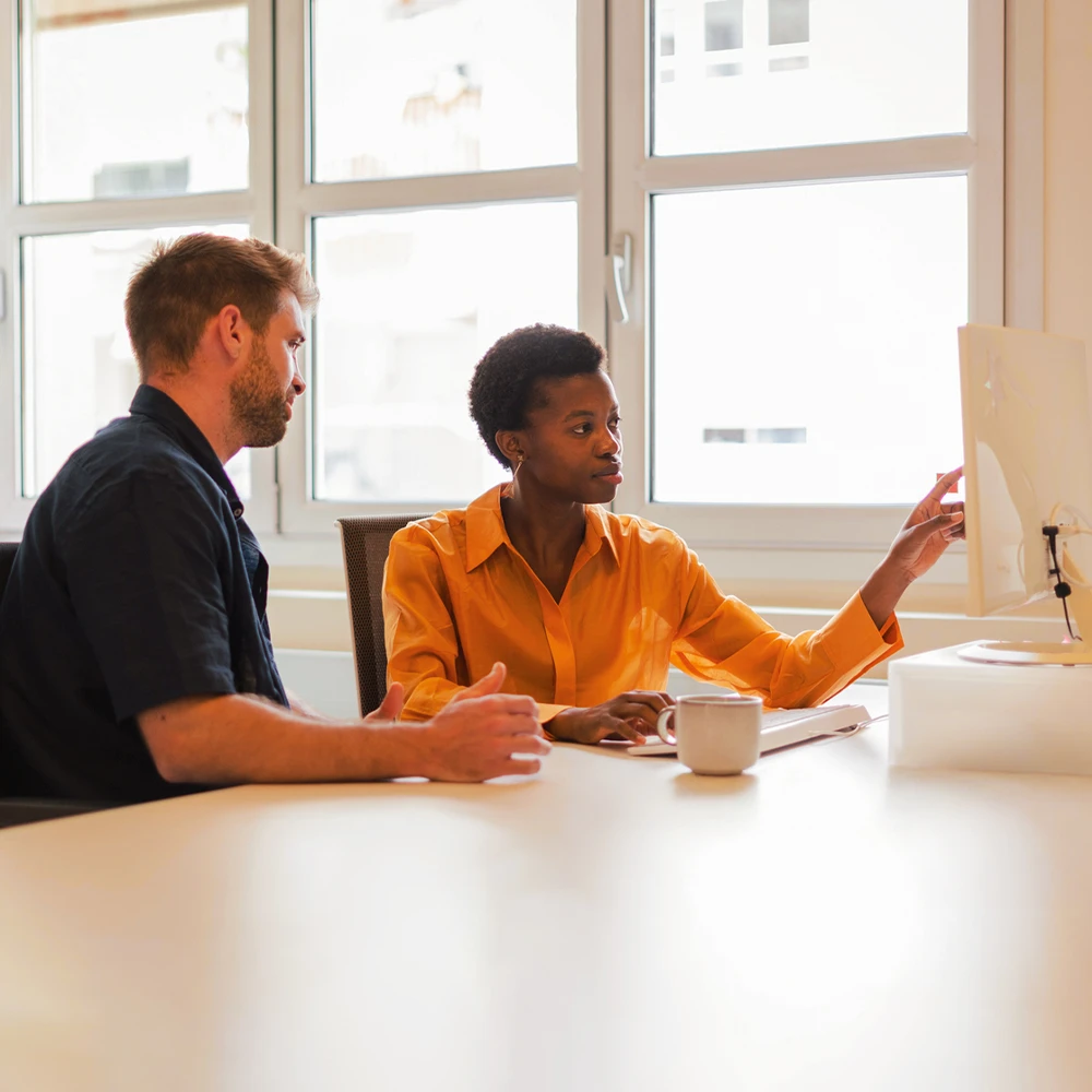 Mitarbeitende, die gemeinsam auf einen Screen sehen und diskutieren