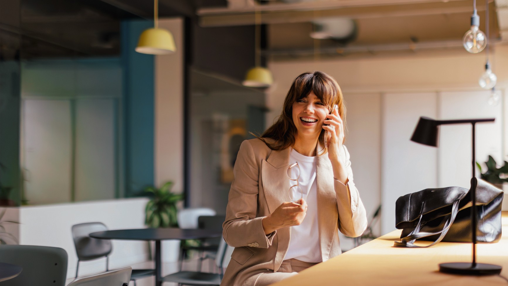 Frau arbeitet am Laptop und telefoniert im Büro.