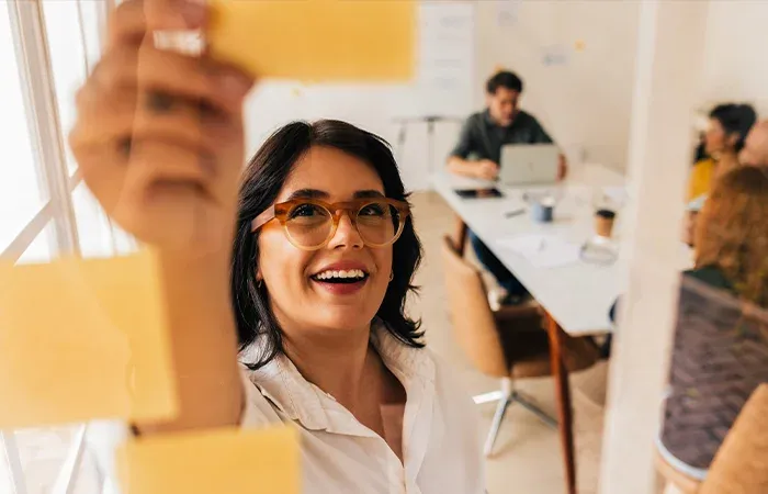 CloseUp einer Frau in einem Büro, die mit ihrem Team über PostIts spricht