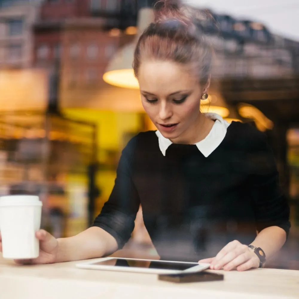 Frau arbeitet in einem Cafe von ihrem Tablet