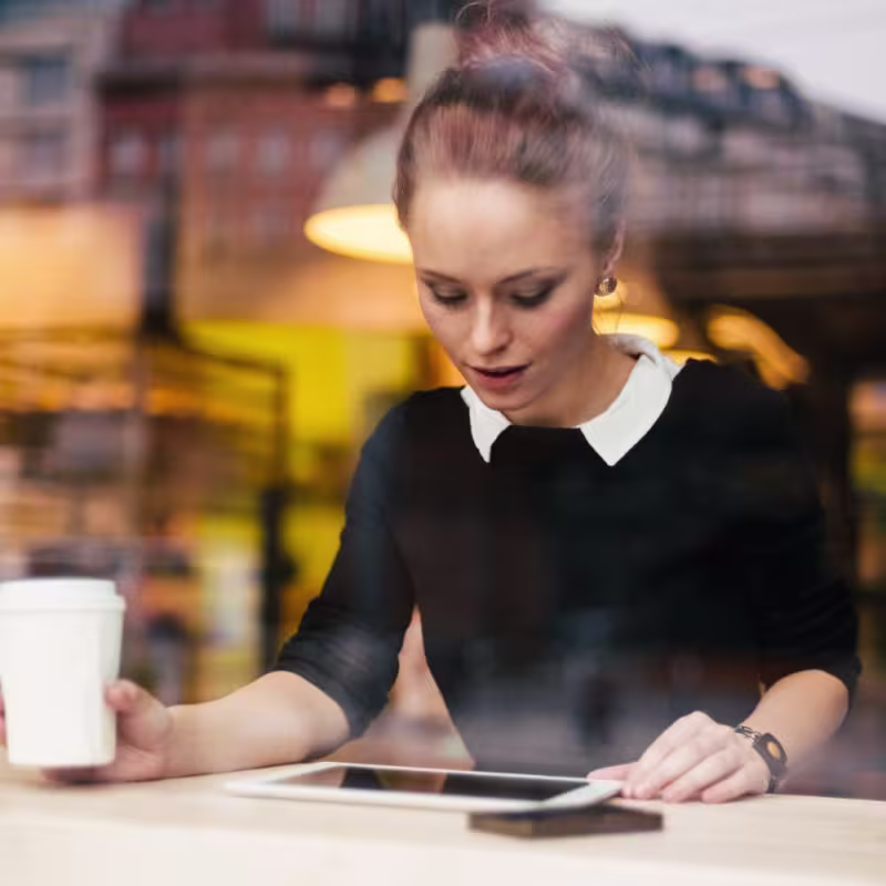 Frau arbeitet in einem Cafe von ihrem Tablet