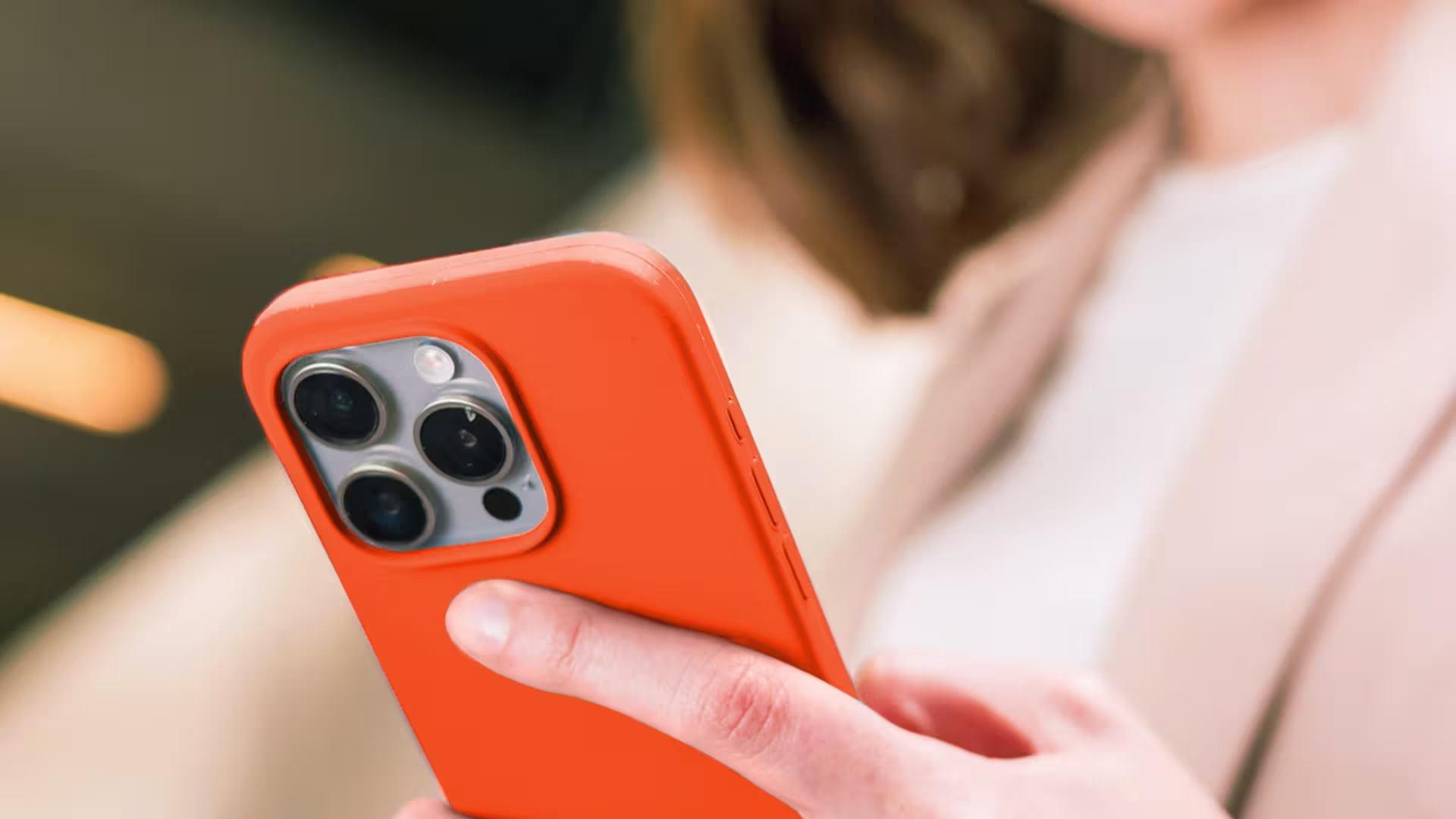 Frau, die ein oranges Smartphone in der Hand hält