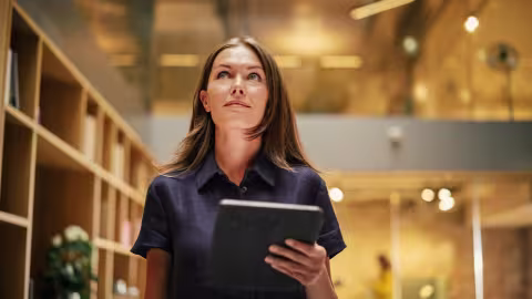 Eine Frau läuft mit einem Tablet in der Hand und schaut nach oben