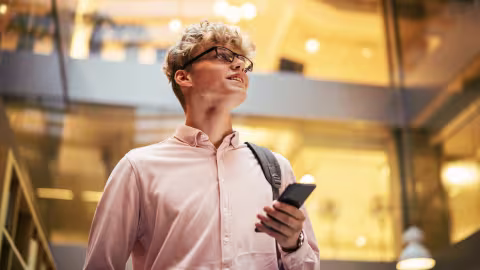 Ein Mann der sein Handy in der Hand hält und auf die Seite schaut