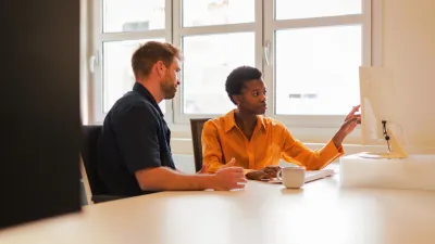 Zwei Mitarbeitende diskutieren etwas gemeinsam auf einen Bildschirm blickend